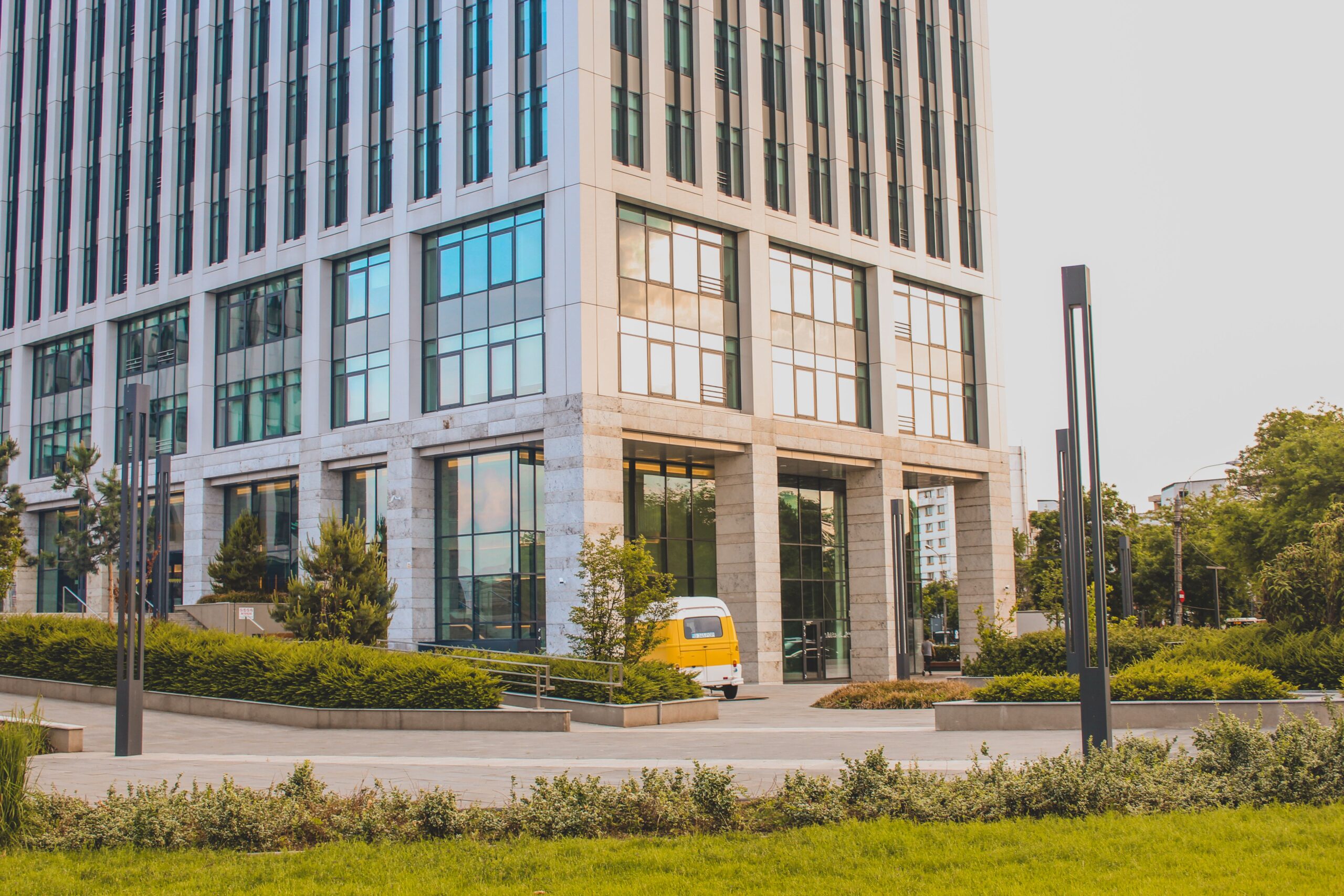 Modern exterior view of a high-rise office building with lush landscaping.